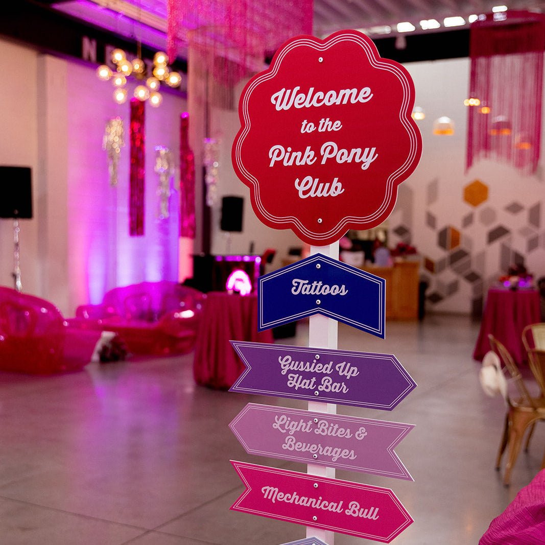 Decorative sign for 'Pink Pony Club' with balloons in a party setting.